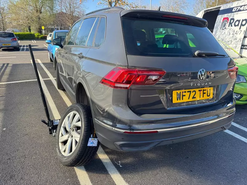 Mobile tyre fitting on a grey Volkswagen Tiguan in a public car park by Rapid Tyres service van.